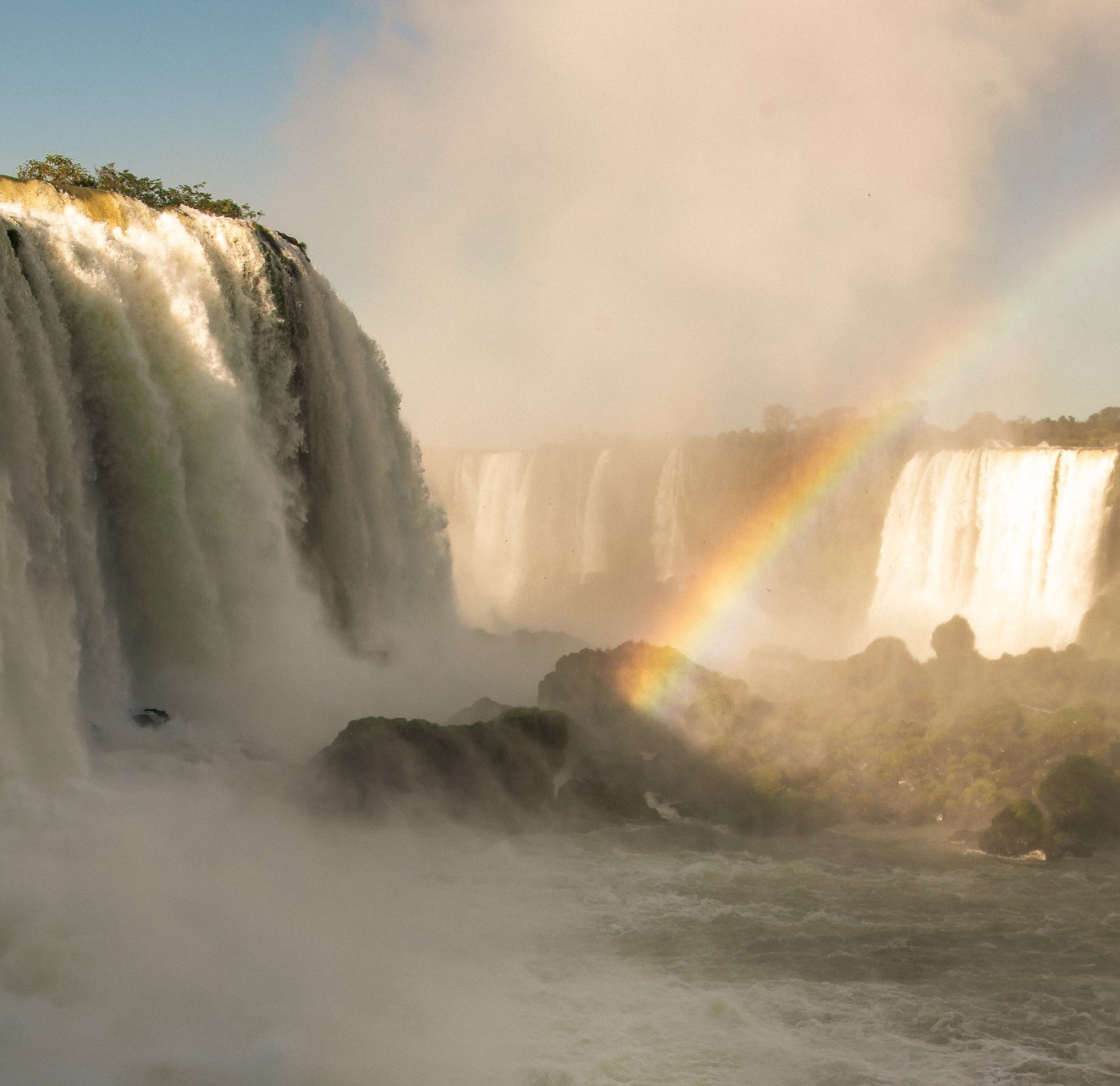 Visitors at Iguaçu Falls with a rainbow in the mist